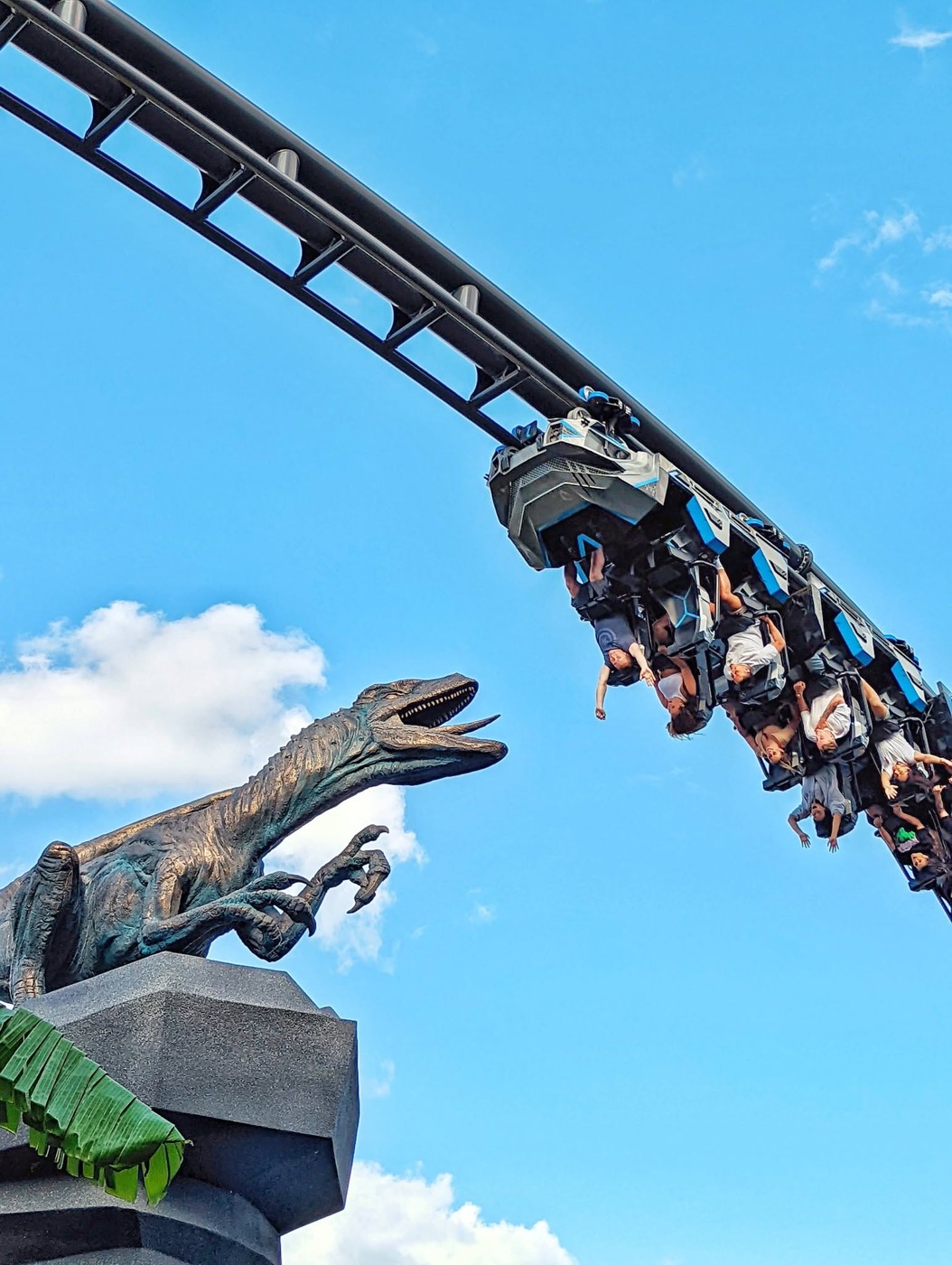 A coaster train racing past a velociraptor sculpture.